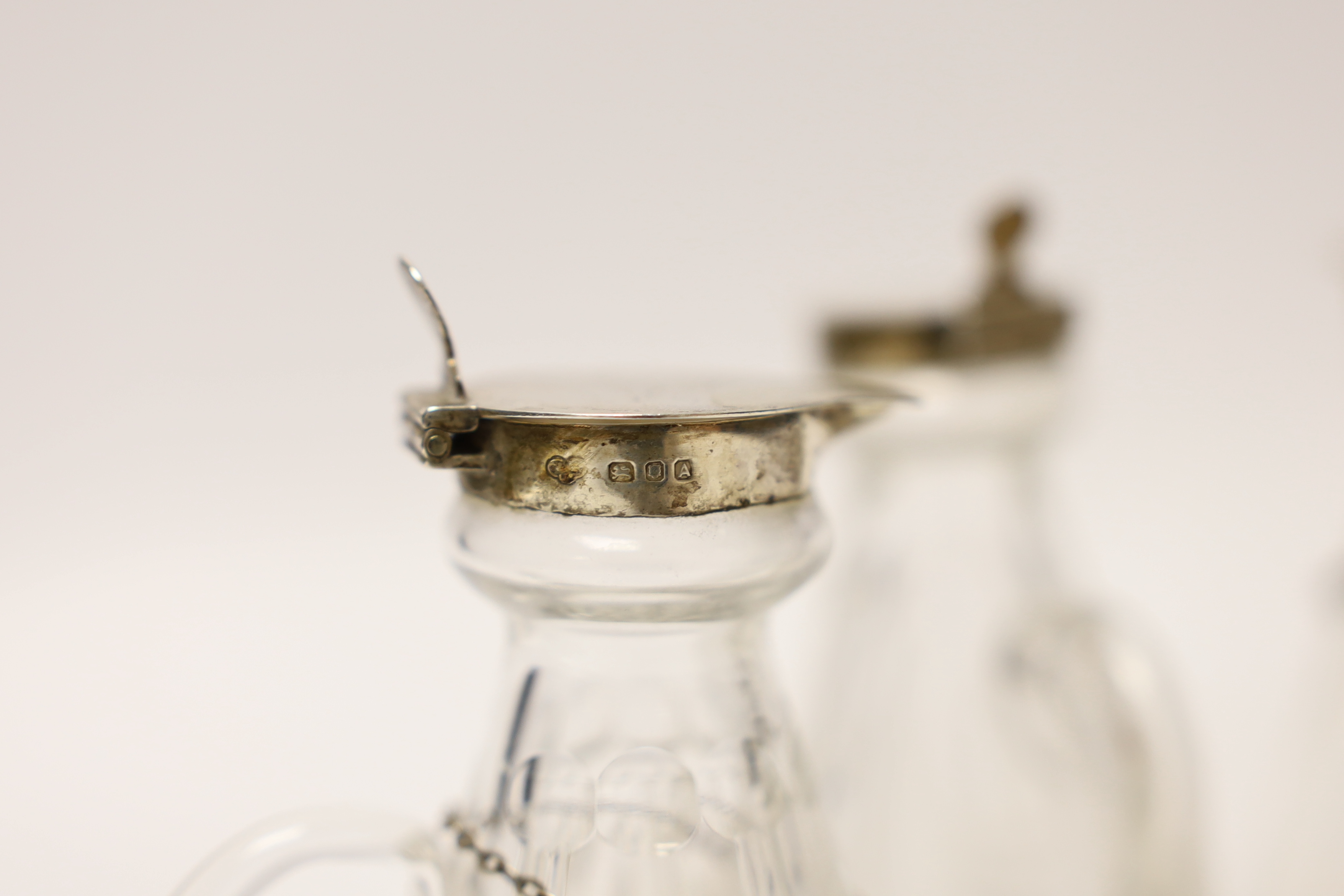 A pair of 1930's silver mounted glass whisky noggins by Goldsmiths & Silversmiths Co Ltd, London 1936, 11.1cm and two other earlier silver mounted glass whisky noggins, together with three silver whisky labels.